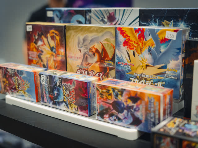 A lit shelf of sealed elite trainer boxes and booster product along the front of a stand.