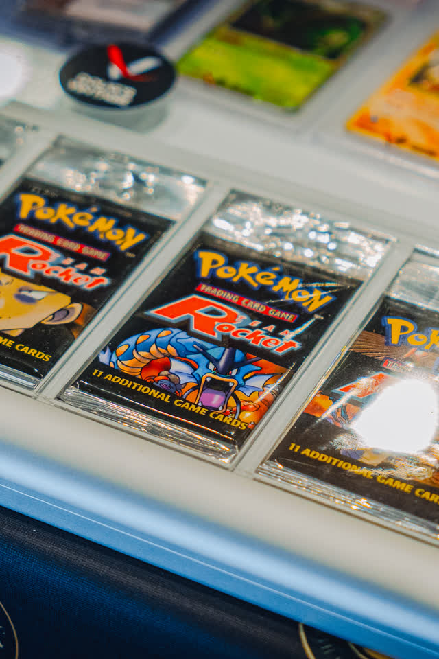 Sealed vintage Pokemon Team Rocket packs stood up in a display case.