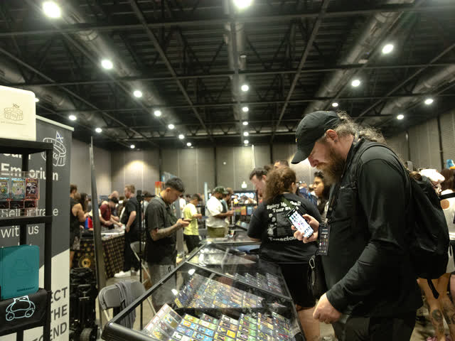 A busy aisle between glass display cases, collectors browsing under the hall lights.