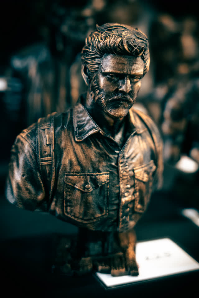 A bronze-finish sculpted bust on display at a maker stand.