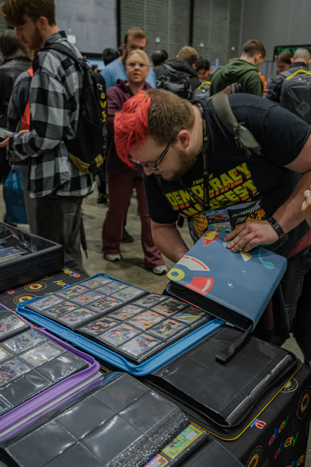 A collector bent over a spread of binders, opening one up on the table.