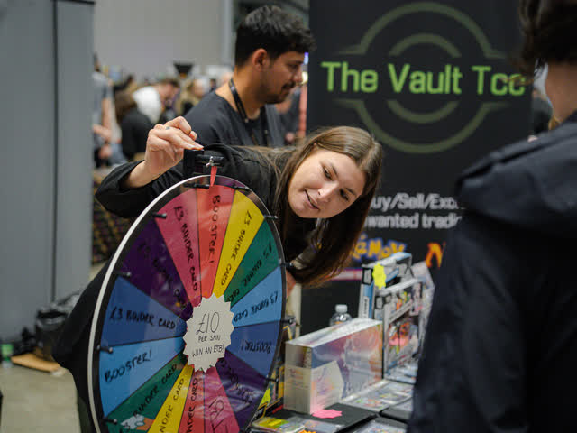 A collector spinning a prize wheel at a vendor stand.