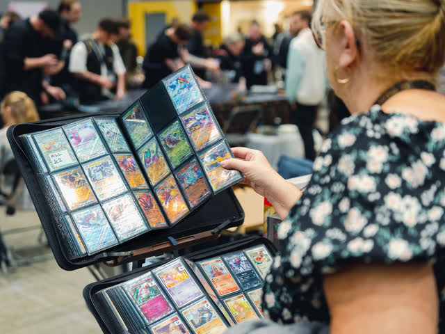 A woman holding a binder of holographic cards open to look along the page.