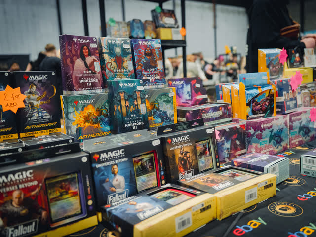 Magic: The Gathering sealed product stacked high across a vendor table.